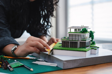 Young architects or student designers carefully works on a detailed architectural model of a modern...
