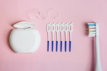 Oral Care: electric toothbrush, dental floss, brush for cleaning interdental spaces on pink background. Concept: dental services and care, oral hygiene