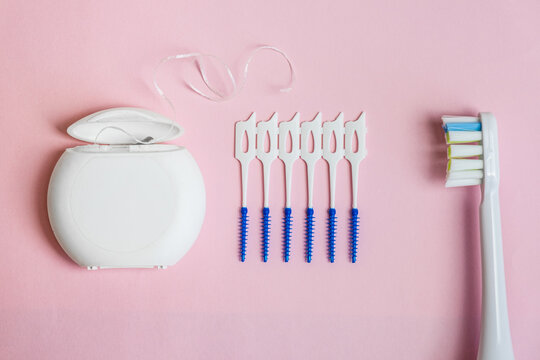 Oral Care: electric toothbrush, dental floss, brush for cleaning interdental spaces on pink background. Concept: dental services and care, oral hygiene