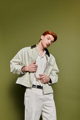Young man expresses emotions with style in contemporary fashion against a green backdrop