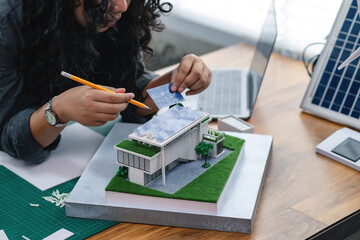 Young architects or student designers are creating architectural models of modern home, eco-friendly homes, simulating solar panels on roof, reflecting creativity eco-friendly home design projects.