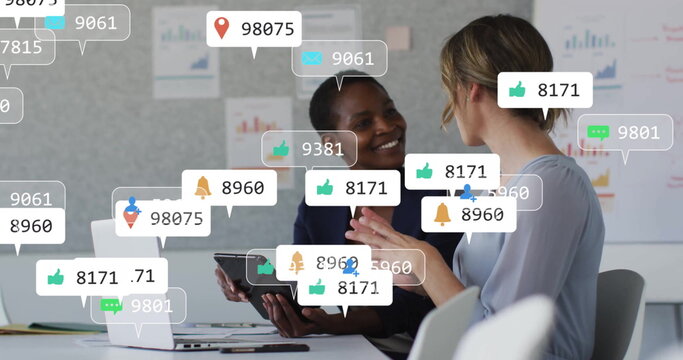 Image of social media icons with numbers over diverse colleagues discussing work in office