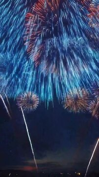 Celebratory fireworks display lighting up the night sky over a quiet town during a summer festival