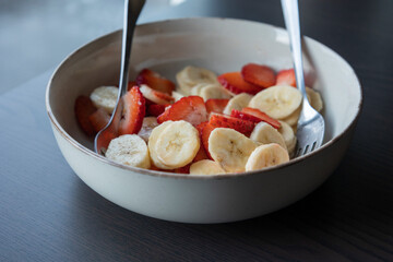 white ceramic bowl full of strawberry and banana slices close-up