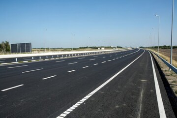 Fototapeta premium Wide-angle shot of black asphalt road with multiple lanes and white dividing lines, urban transportation, highway design, multiple lanes, black asphalt road, road network