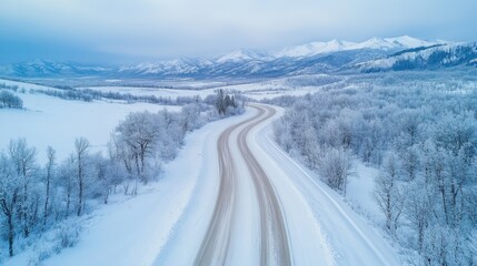 Obraz premium Winter road in Alaska. Snowy landscape. Mountains in background. Cold weather. Frozen trees. Empty road. Travel and scenic views.