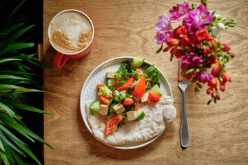 flatbread with tomatoes, cucumber, lettuce and tofu. Wooden background, side view