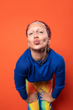 Fashionable individual in vibrant outfit against orange backdrop