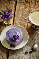 Vegan raw blueberry cheesecake. Wooden background, viola, blueberry 