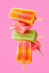 Brightly colored popsicles stacked against vibrant pink backdrop