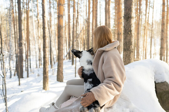 Anonymous woman and border collie enjoy winter forest moment