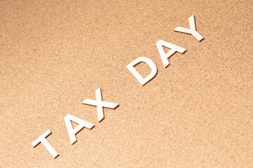 Tax Day: Diagonal wooden text on cork board, tax deadline concept.