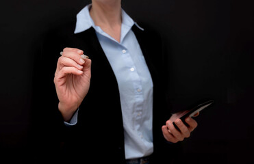 Close up of Businesswoman using stylus pen to write on virtual screen and holding smartphone on...