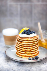 Stack of freshly prepared lemon poppy seed pancakes topped with sour cream and blueberries