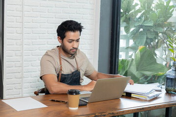 Attractive barista male or employee concentrate on stacks of tax declaration bills, restaurant owner using laptop for bookkeeping control payment, multitask small business lifestyle doing everything