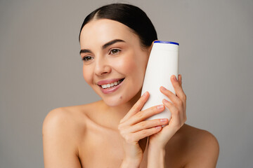 A cheerful individual beautiful female model girl displaying a shampoo bottle, symbolizing personal...