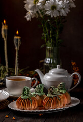 Delicious pumpkin shaped cakes with tea for autumn celebration