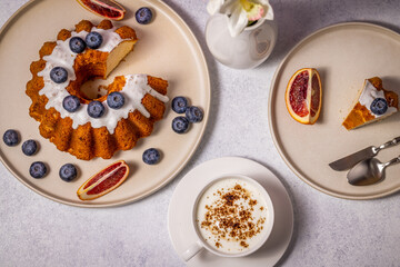 Delicious gugelhupf cake with blueberries, blood orange, and cappuccino for perfect breakfast