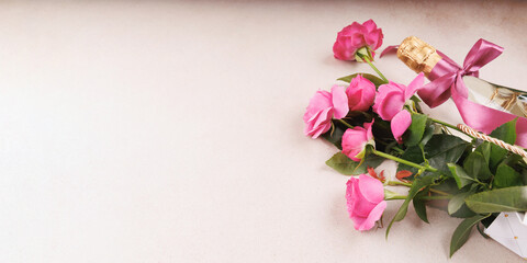 A stylish arrangement featuring a champagne bottle with a pink ribbon and a bouquet of pink roses in a gift bag.