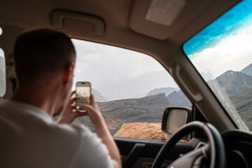 Fototapeta premium Roadtrip durch die Berge Omans Mann macht foto mit dem Mobiltelefon aud dem Fenster