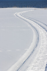Snowmobile tracks leading to sea over white snow surface
