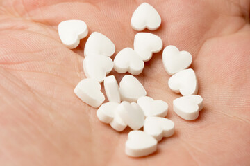 The medical concept of diseases of the human cardiovascular system. A heart-shaped tablet on a person's arm.