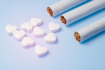 The medical concept of diseases of the human cardiovascular system. Cigarettes and a pill in the shape of a heart. Selective focus.