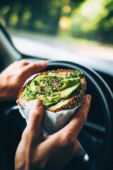 A man eating an avocado and egg sandwich while driving, with the sandwich wrapped in a thick napkin for convenience. The bread is toasted on both sides, with  egg inside,  yolk ,Creamy avocado 