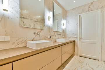 A spacious modern bathroom featuring marble walls and elegant fixtures, providing a sleek and sophisticated ambiance. The design emphasizes comfort and minimalism.