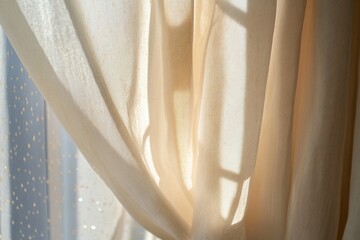 A close-up shot of a curtain with a window visible through it