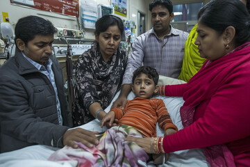 Young Indian boy waiting at an emergency room, Family gathering around worried.
