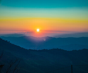 The stunning view from a tourist's standpoint as they go down a hill on a foggy trail with a hill and a background of a golden sky in Forest Park, Thailand. Rainforest. Bird's eye view. Aerial view.