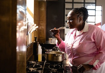 Senior woman tasting soup in kitchen, enjoying cooking class experience, copy space