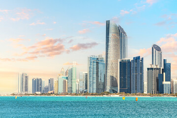 Modern skyscrapers reflecting on turquoise sea at sunset in Abu Dhabi, United Arab Emirates