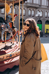 Cheerful young pretty woman in sunglasses with brown hair walking in park of attractions, wearing casual clothes