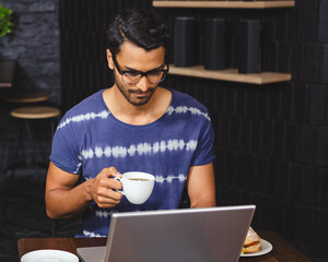 Man enjoying coffee while working on laptop in cozy coffee shop