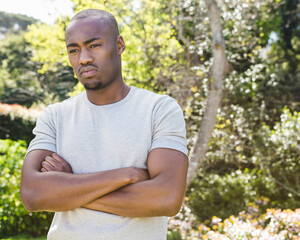 African American man standing outdoors with arms crossed, looking thoughtful