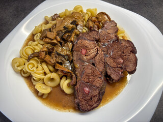 White plate with delicious beef with mushrooms and pasta
