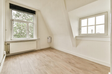 A spacious, minimalistic room with light-colored walls and wooden flooring, featuring two windows that allow natural light to fill the space.