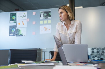 Analyzing data charts, businesswoman planning strategy in modern office setting