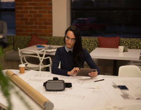 Architect reviewing blueprints on tablet in modern office, focused on design