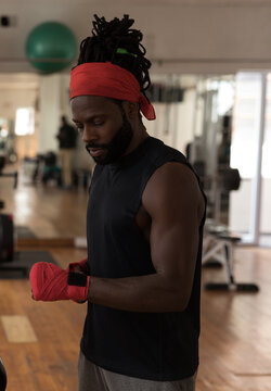 Man in gym wrapping hands with red bandages, preparing for workout session