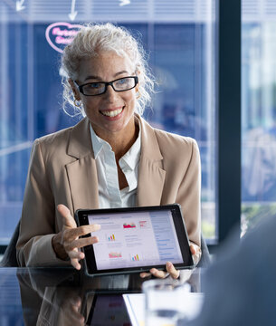 In office, businesswoman presenting financial data on tablet, smiling confidently