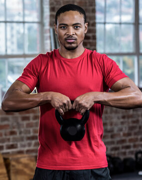 Lifting kettlebell in gym, man building strength and focusing on exercise