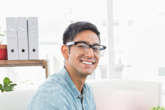 Smiling man in glasses sitting in modern office, looking confident and relaxed