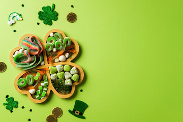 Clover tray of green and white candies, surrounded by shamrocks, gold coins, and leprechaun hats on...