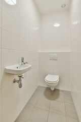 A clean and minimalist restroom interior featuring white tiles, a simple sink, and a toilet, showcasing contemporary design elements in a well-lit space.