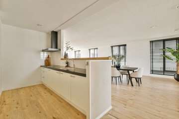 A sleek and stylish kitchen showcasing modern design with wooden flooring, natural light, and a blend of functional elements and greenery for a fresh atmosphere.