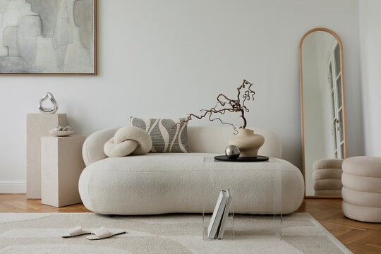 Modern living room with a curved white sofa, textured rug, and sculptural decor in a calming neutral palette. - Powered by Adobe