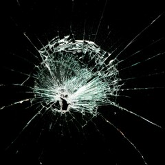 Broken glass with central impact and radial cracks on a black background, highlighting details of the fractured crystal. Shattered glass texture with light effects on the cracks
